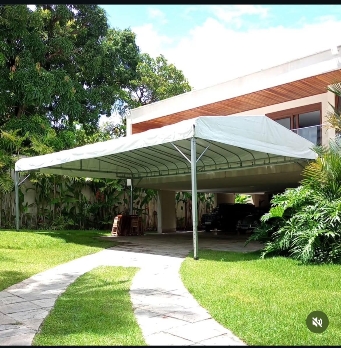 Tenda branca cobrindo entrada de residência com jardim